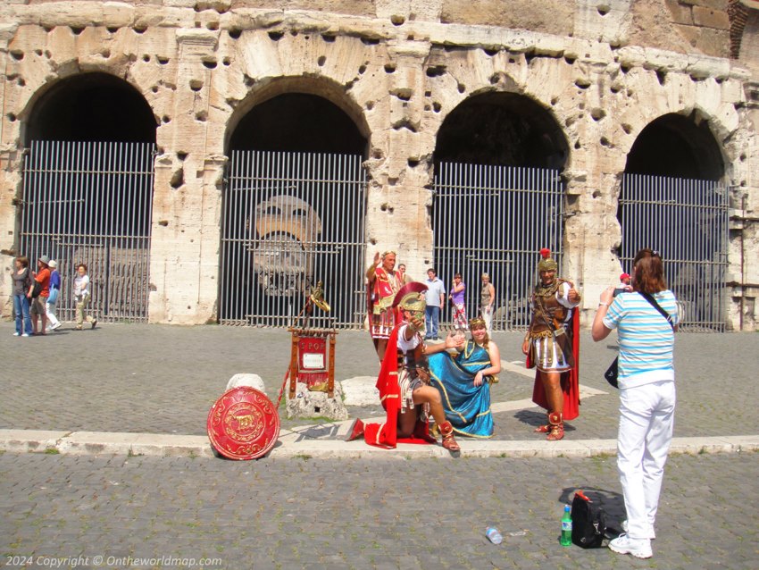 Tourists take photos with legionaries of the Roman Empire against the backdrop of the Colosseum